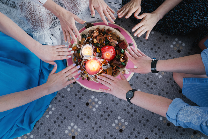 Women's circle. Female hands holding a bowl with candles and rose petals